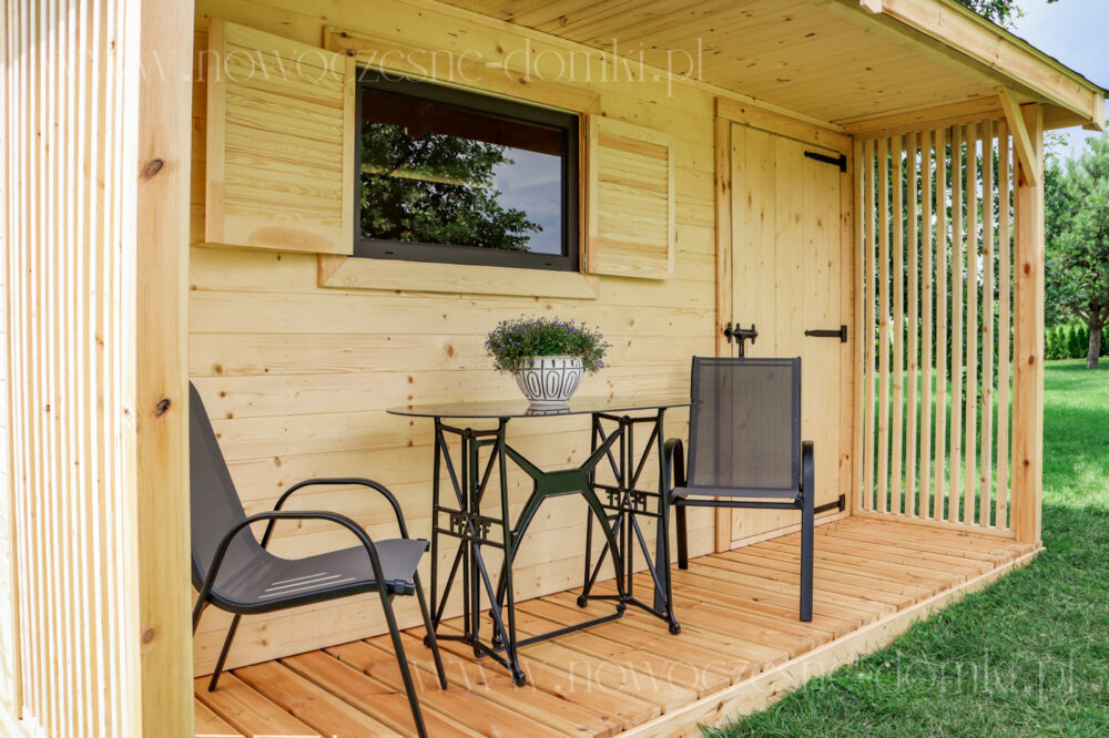 Taras domku ogrodowego z dwoma krzesłami oraz stolikiem i drewnianą podłogą