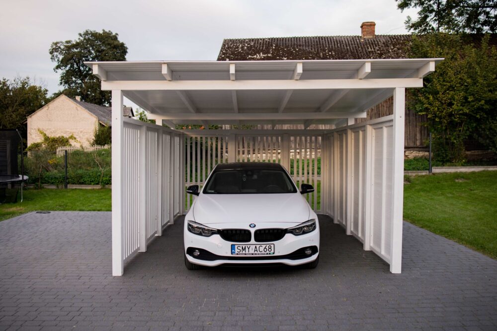 Wiata samochodowa z dachem jednospadowym wykonana z drewna w której znajduje się pojazd marki BMW