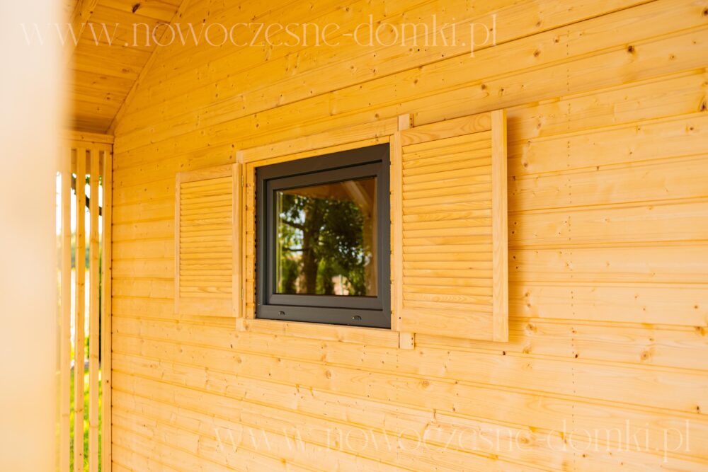 Obszerny taras z drewnianymi oknami - letni domek w harmonii z przyrodą.