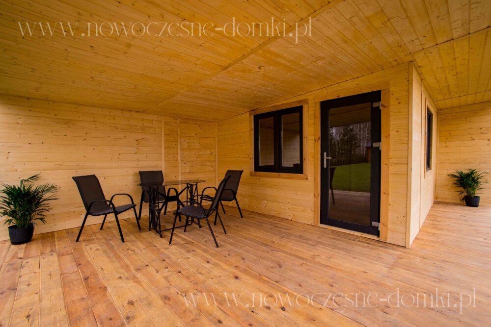 Przestronny taras drewnianego domku letniskowego - Uroczy drewniany domek letniskowy z przestronnym tarasem.