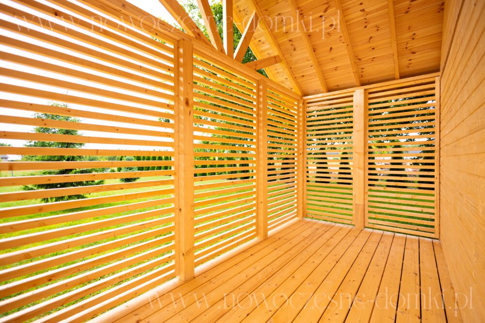 Taras drewnianego domku na działce ROD - idealne miejsce na relaks podczas wakacji.
