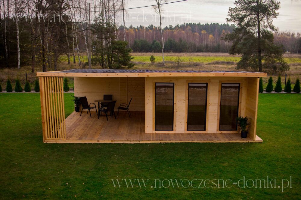 Drewniany domek ogrodowy z tarasem dla relaksu - Urokliwy domek letniskowy w ogrodzie, zapewniający komfortowy taras idealny do relaksu i odpoczynku.