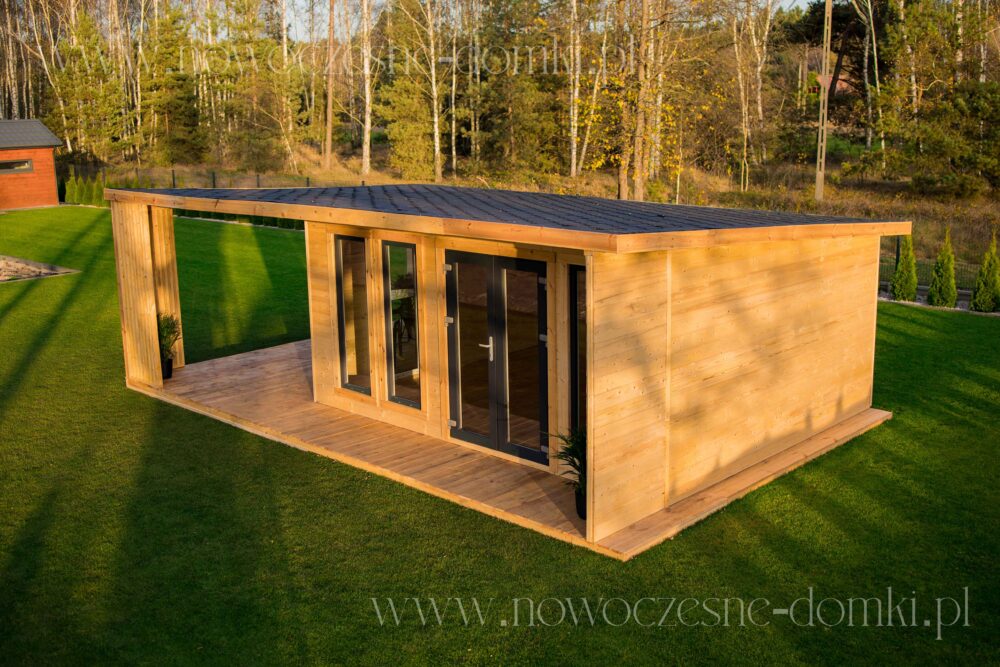 Przeszklony drewniany domek ogrodowy z tarasem - harmonijne połączenie wnętrza z naturą.